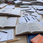 Sala de provas em Brasília com kit de primeiros socorros e papéis de concurso, representando lei da CLDF que eleva estresse em concursos no DF.