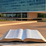 Fachada da Câmara Legislativa do DF em Brasília com Bíblia aberta em pedestal, representando polêmica sobre laicidade.