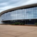 Edifício governamental em Brasília com documentos fiscais e moedas, representando elevação de custos públicos por folga de servidores no aniversário.