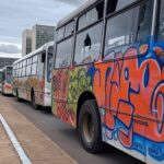 Ônibus vandalizados em rua de Brasília, com danos como vidros quebrados e pichações, em investigação da PCDF.
