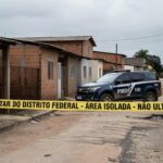 Rua residencial no Recanto das Emas com fita de isolamento policial e viatura da PMDF, representando cena de feminicídio.