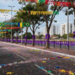 Rua em Brasília decorada para Carnaval com fitas roxas simbolizando campanha contra assédio em blocos.
