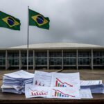 Sala de audiência pública na Câmara Legislativa do DF com documentos de falhas fiscais expostos, em Brasília.
