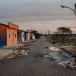 Rua em Riacho Fundo I com casas antigas reformadas tardiamente e problemas de infraestrutura persistentes.