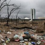 Paisagem degradada no Cerrado do DF com Câmara Legislativa ao fundo, destacando críticas à ineficácia ambiental.