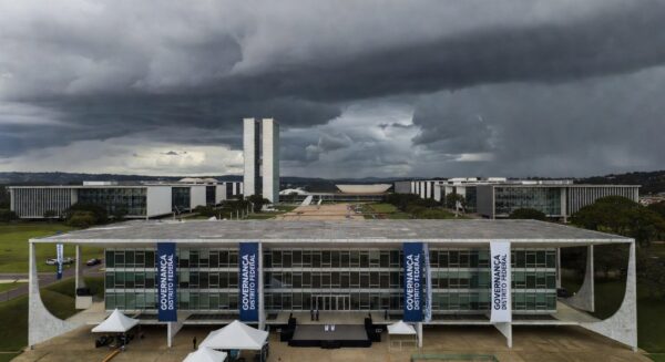 Edifício da CLDF em Brasília com decorações de evento de governança e nuvens escuras ao fundo, representando distração para crises no DF.