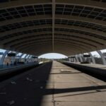 Estação de metrô em Brasília com trilhos vazios e documentos burocráticos, representando atrasos em contratações no Metrô-DF.