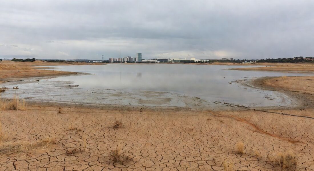 Reservatório de água com nível baixo em Brasília, destacando falhas na segurança hídrica do DF no aniversário da Caesb.