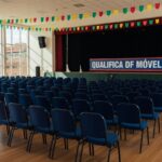 Auditório no Paranoá com palco e banner do QualificaDF Móvel para formatura de alunos.