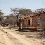 Cena de crime em casa rural de Planaltina, DF, com fita de isolamento e viaturas policiais, representando chacina familiar.