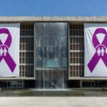 Edifício governamental em Brasília com símbolos de campanhas contra violência doméstica, representando expansão de programas da Sejus-DF.