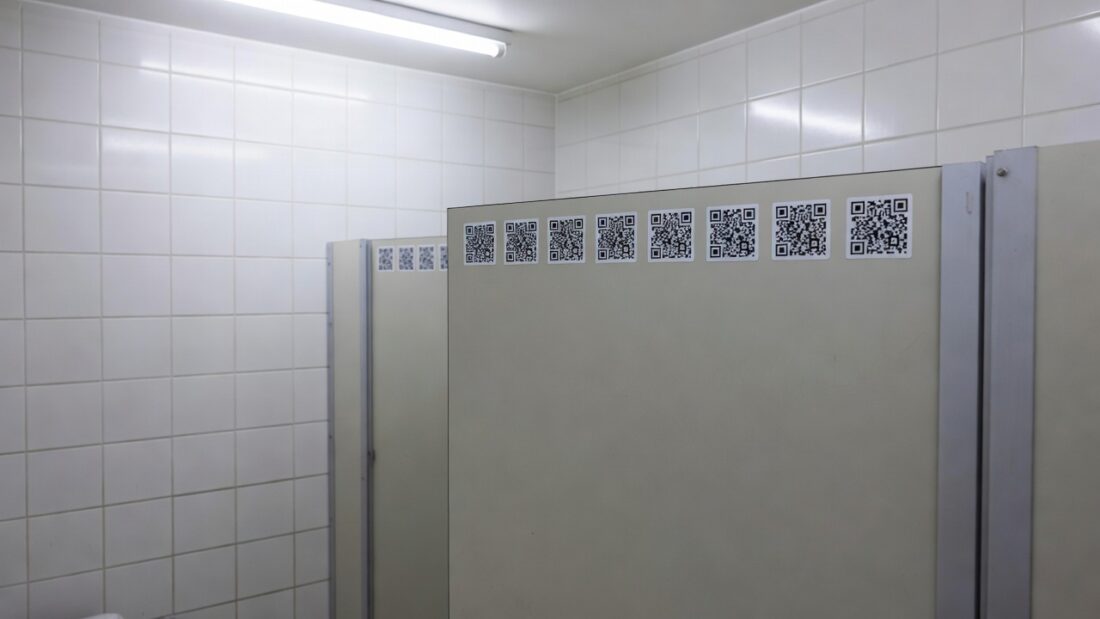 Adesivos com QR Code em banheiro público do DF para ajudar vítimas de violência