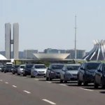 Carreata em rodovia no DF com skyline de Brasília ao fundo